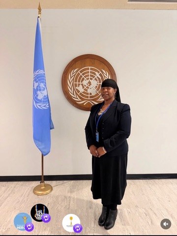 Dr. Lakisha beside a United Nations flag and emblem
