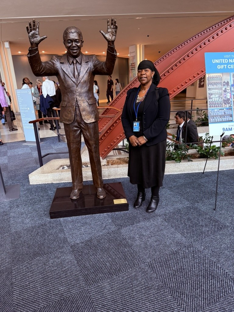 Dr. Lakisha standing beside a statue inside the United Nations building